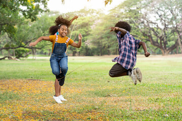 Group of African American children having fun jumping over the rope in the park. Education or Field trip concept
