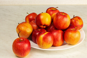 Red apples are on a white plate. Close up
