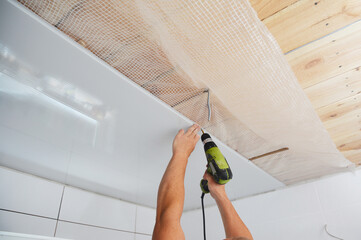 Installing wall and ceiling panels on planked wood ceiling covered with vapor barrier membrane...