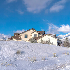 Square Mountain home with towering Wasatch peaks and cloudy blue sky background