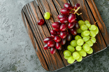 Red and green grapes on a wooden board