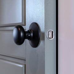 Square frame Hinged panel wooden door with round black door knob and protruding latch