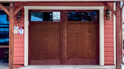 Panorama frame Brown wooden glass panelled garage door of home under snowy roofs in winter