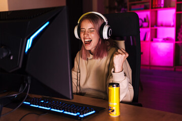 Image of girl making winner gesture and playing video game on computer