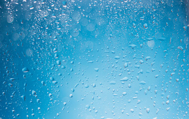 Naklejka na ściany i meble Blue water drops background. Blue water drops on a boat glass background. Water drops on boat glass blue bokeh background.