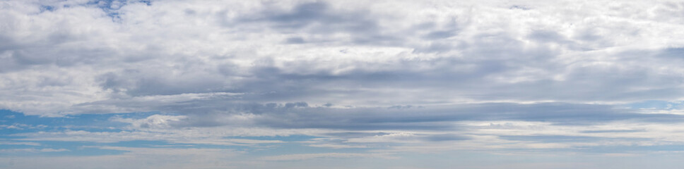 Panorama of blue sky with dense white and gray clouds