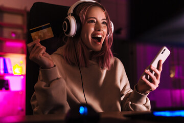Image of excited girl holding credit card and using cellphone © Drobot Dean