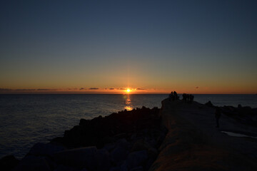 太平洋の初日の出を岩場で眺める人々