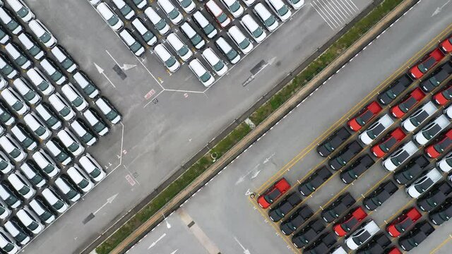 Aerial helicopter view of flying over car parking lot of brand new export cars in industrial zone. Many car waiting for transportation at port  