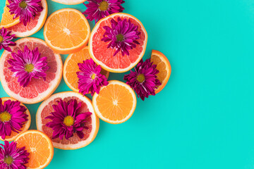 Colorful pattern made of slices of citrus fruits (orange, grapefruit) with purple flowers  in a turquoise background