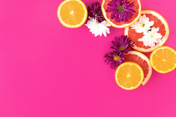 Citrus fruits cut with flowers in a fucsia background