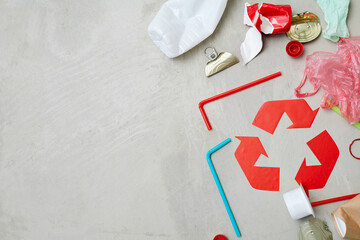 Close-up of red recycling symbol with waste isolated on grey background
