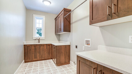 Panorama Kitchen interior with brown wooen cabinets white countertops sink and window