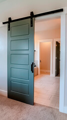 Vertical Sliding gray wooden panel door that leads to the bathroom of a home