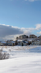 Vertical crop Wasatch Mountain in winter with houses on sunlit acres of snow covered terrain