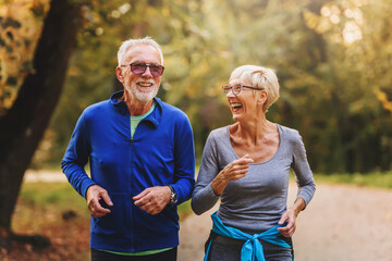 Smiling senior couple jogging in the park - obrazy, fototapety, plakaty