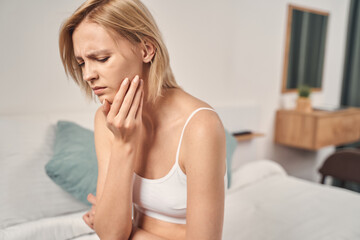 Depressed young blonde woman having a toothache