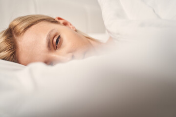 Sleepy blonde woman in bed looking forward