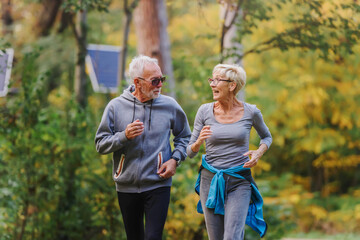 Fototapeta premium Smiling senior couple jogging in the park