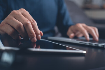 casual man working on digital tablet and laptop computer at home office