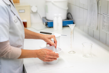 close up view of a pharmacist in the laboratory mixing a medical ointment in a bowl