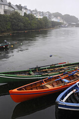 Fototapeta na wymiar Trois barques colorées, verte, orange et bleue accostées dans un petit port à l'ouest de l'Irlande.