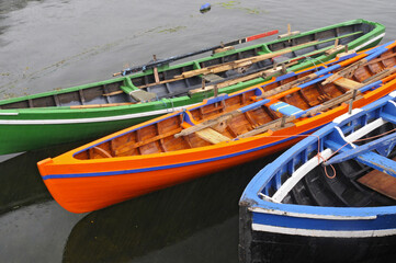 Trois barques colorées, verte, orange et bleue accostées dans un petit port à l'ouest de l'Irlande.