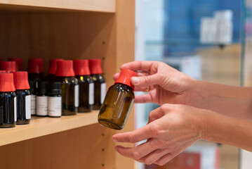 hands of a female pharacist arranging normed brown glass apothecary bottles with sealed caps and droppers on a shelf