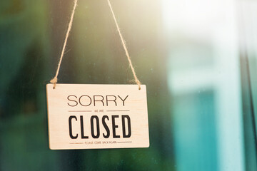 Close up of SORRY WE ARE CLOSED PLEASE COME BACK AGAIN notice sign wood board label hanging through glass door front shop, Business close during coronavirus disease concept