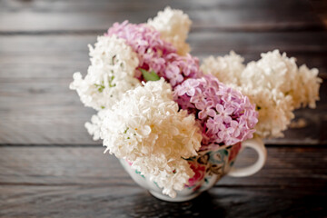 A beautiful bouquet of spring lilac on a dark wooden background.