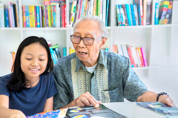 Old man help his granddaughter to study in library