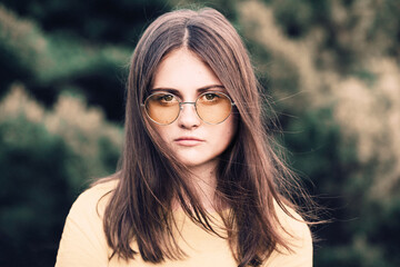 Portrait of a teenage girl with long hair in a yellow glass