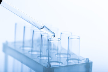 pipette with a drop and scientific laboratory test tubes in a research laboratory.