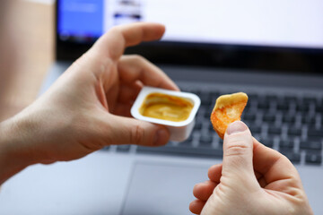 Hands holding mustard and potatoes near laptop