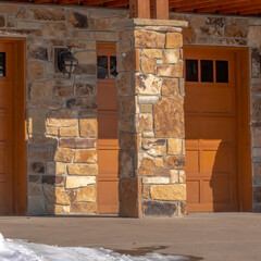 Square Garage entrance of a home with stone brick wall and balcony in snowy Park City