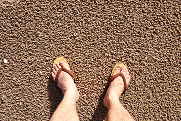 Topview tourist foots which wear slippers stand on the beach on summer vacation time, picture have space for idea.