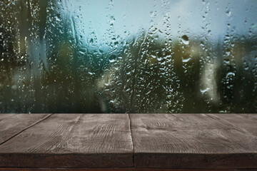 Wooden table near window on rainy day