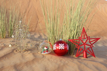 Shiny Christmas tree bauble in desert sand dune. Merry Christmas/Christmas/Happy Holidays/Season's...