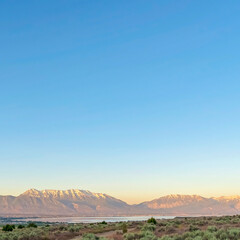 Square Rough road on grassy terrain with view of scenic lake and snow capped mountain