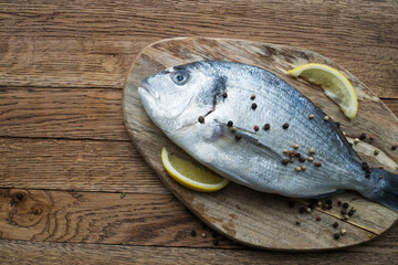 Raw fish cooking and ingredients. Dorado, lemon, herbs and spices. Top view on stone table