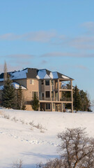 Fototapeta na wymiar Vertical crop Wasatch Mountains snowy neighborhood with beautiful house against blue sky