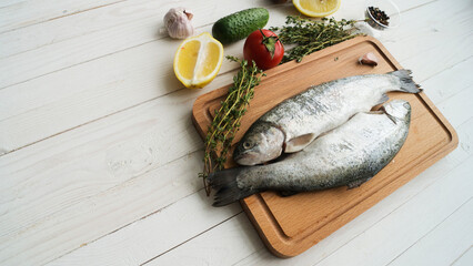 Two rainbow trout on a board, with herbs , ready for cooking.