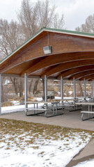 Vertical Pavilion with wooden arches on the ceiling amid park covered with snow in winter