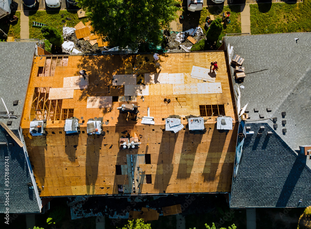 Wall mural A worker replace shingles on the roof of a home repairing the roof of home