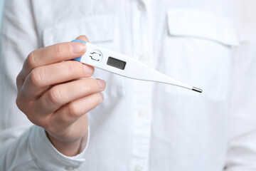 Woman holding modern digital thermometer, closeup view