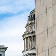 Square Utah State Capital building and dome viewed behind a stone building exterior