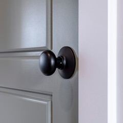 Square frame Gray wooden hinged door with black door knob and panels inside of home