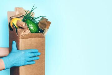Food delivery service during coronavirus pandemic. Hands in medical gloves carrying package box of...
