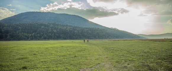 Biker couple on a grassy field with a mountain forest int he background