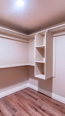 Fototapeta premium Vertical Spacious walk in closet of new home with metal rods shelves and wooden floor